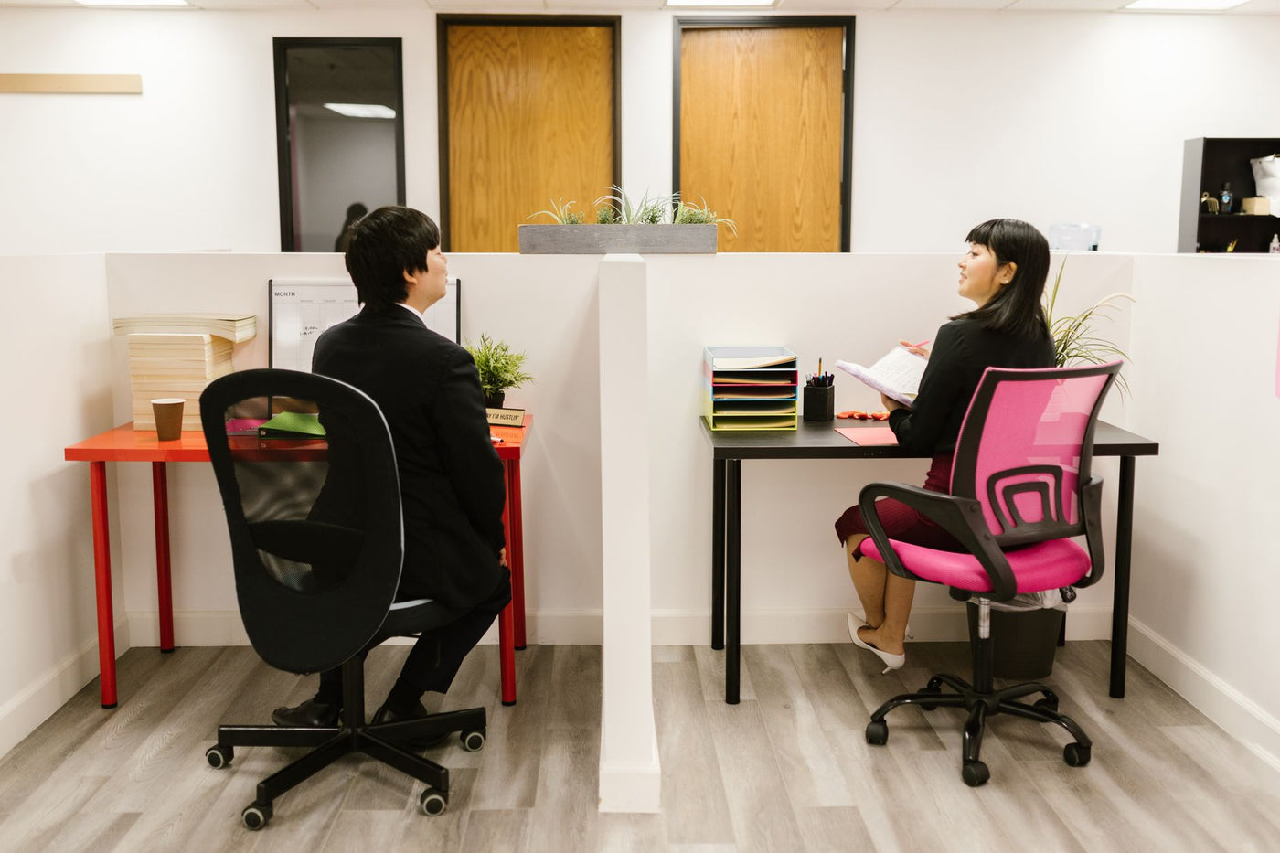 Asian coworkers discussing in a modern office setup, highlighting teamwork and collaboration.