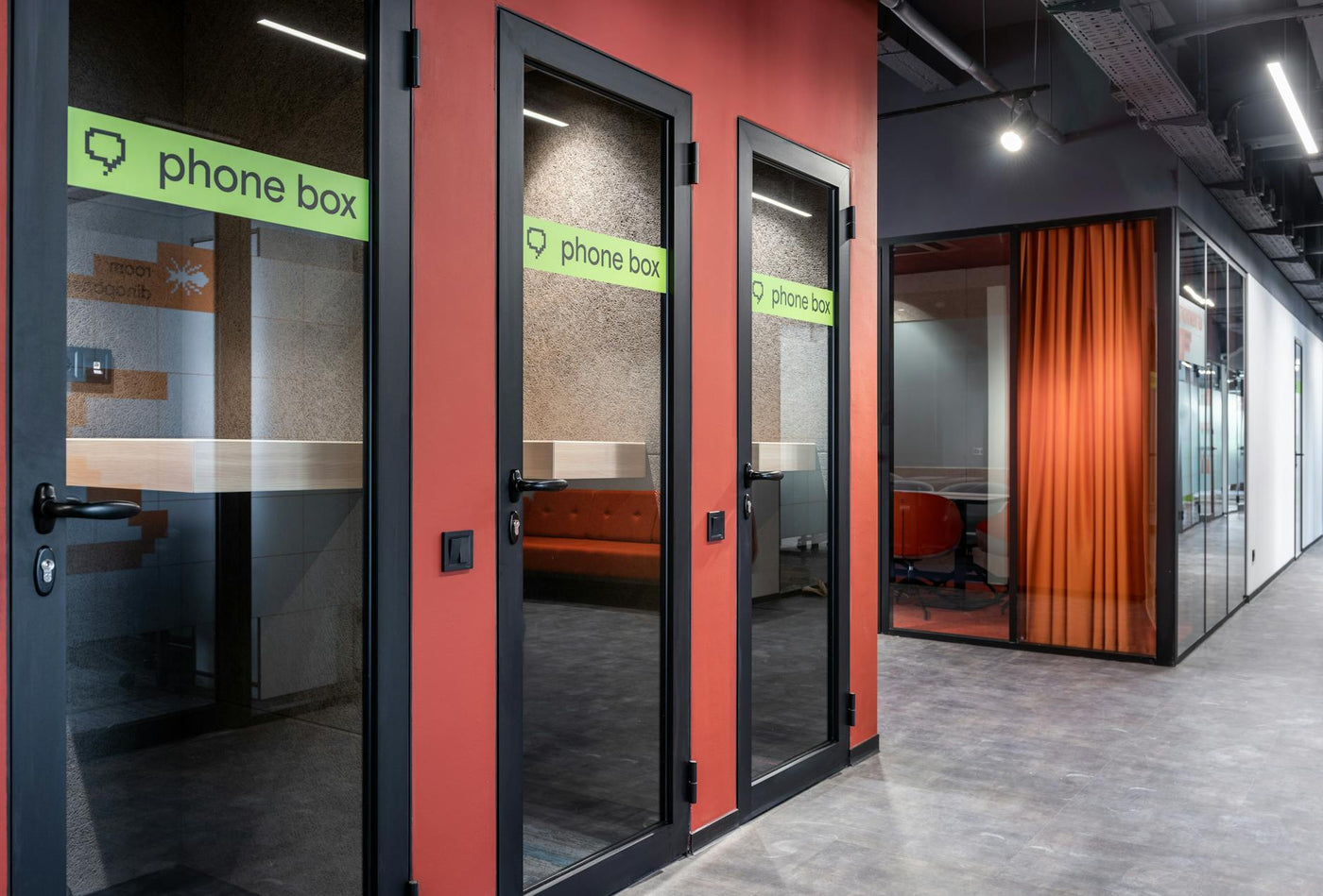Phone boxes with inscription on glass doors and conference room with red curtain and chairs in hall of contemporary business center