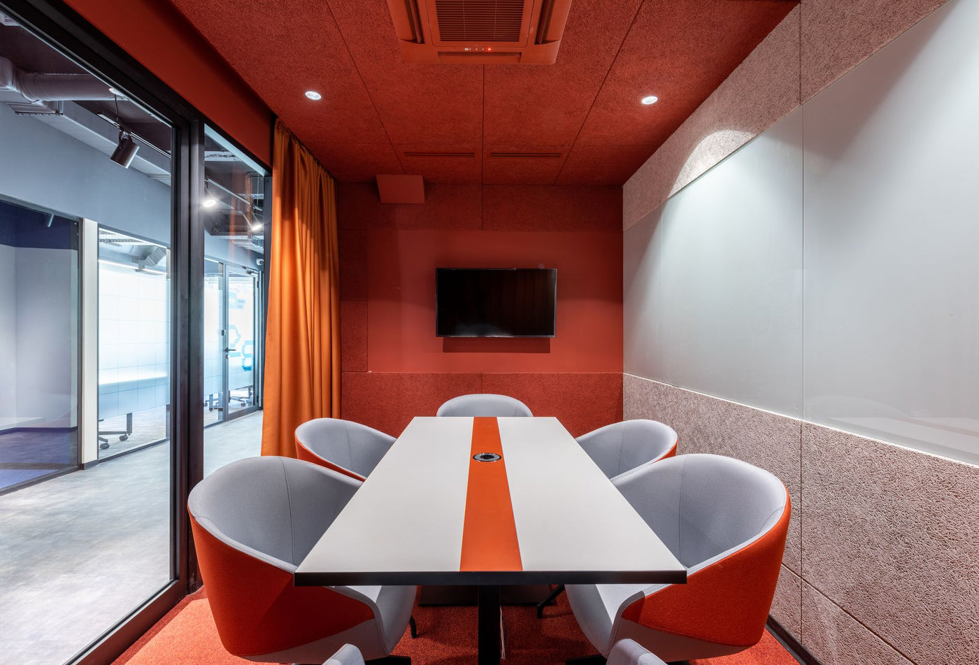 Comfortable chairs at tale placed against red wall with TV in modern conference room with glass wall in business center