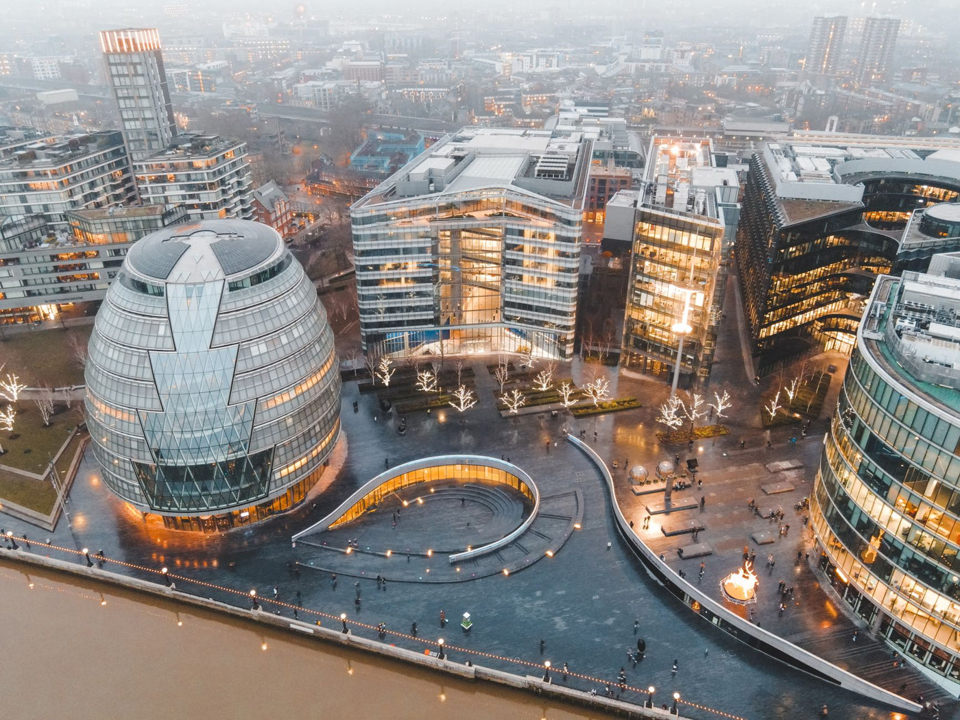 Aerial view of London's modern skyline with iconic architecture illuminated at dusk.