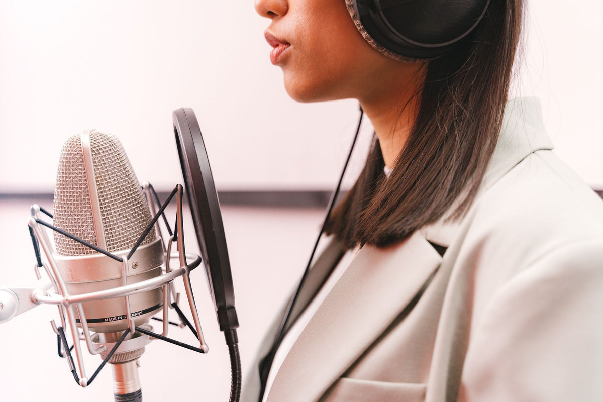Female singer recording her music in a studio with a condenser microphone.