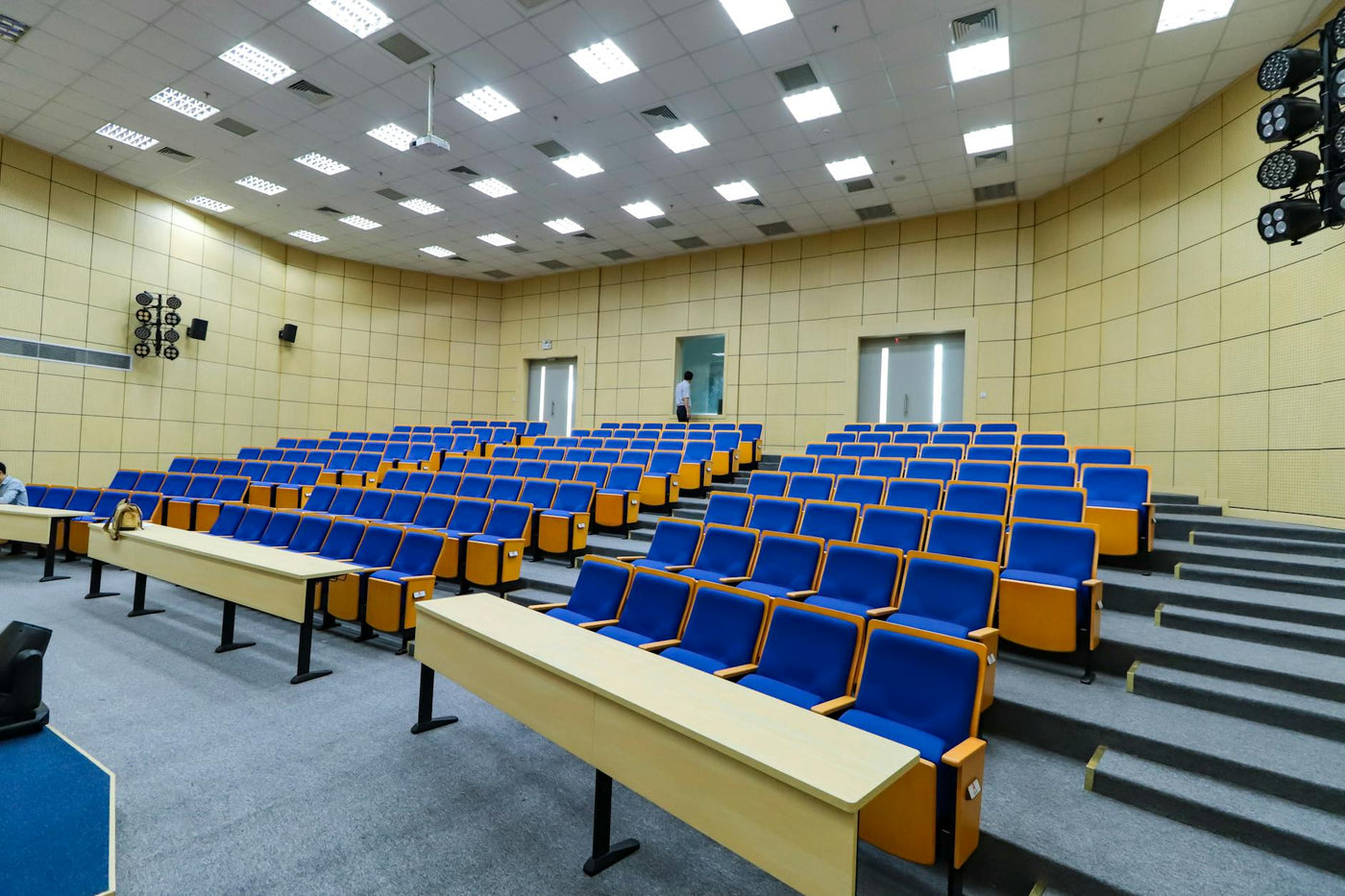 Spacious lecture hall with blue seats and desks ready for students.