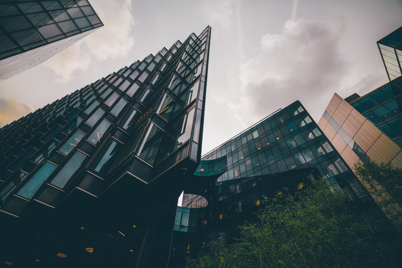 Low angle view of sleek modern buildings in London with dramatic cloudy sky.