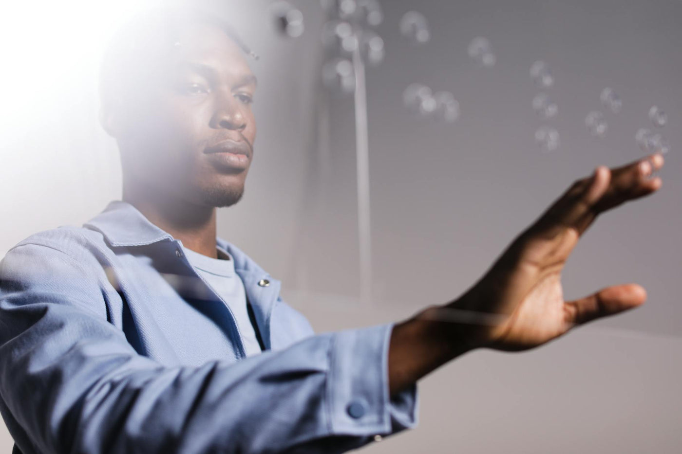An African American man touches a virtual interface, demonstrating kinesthetic interaction and technology.