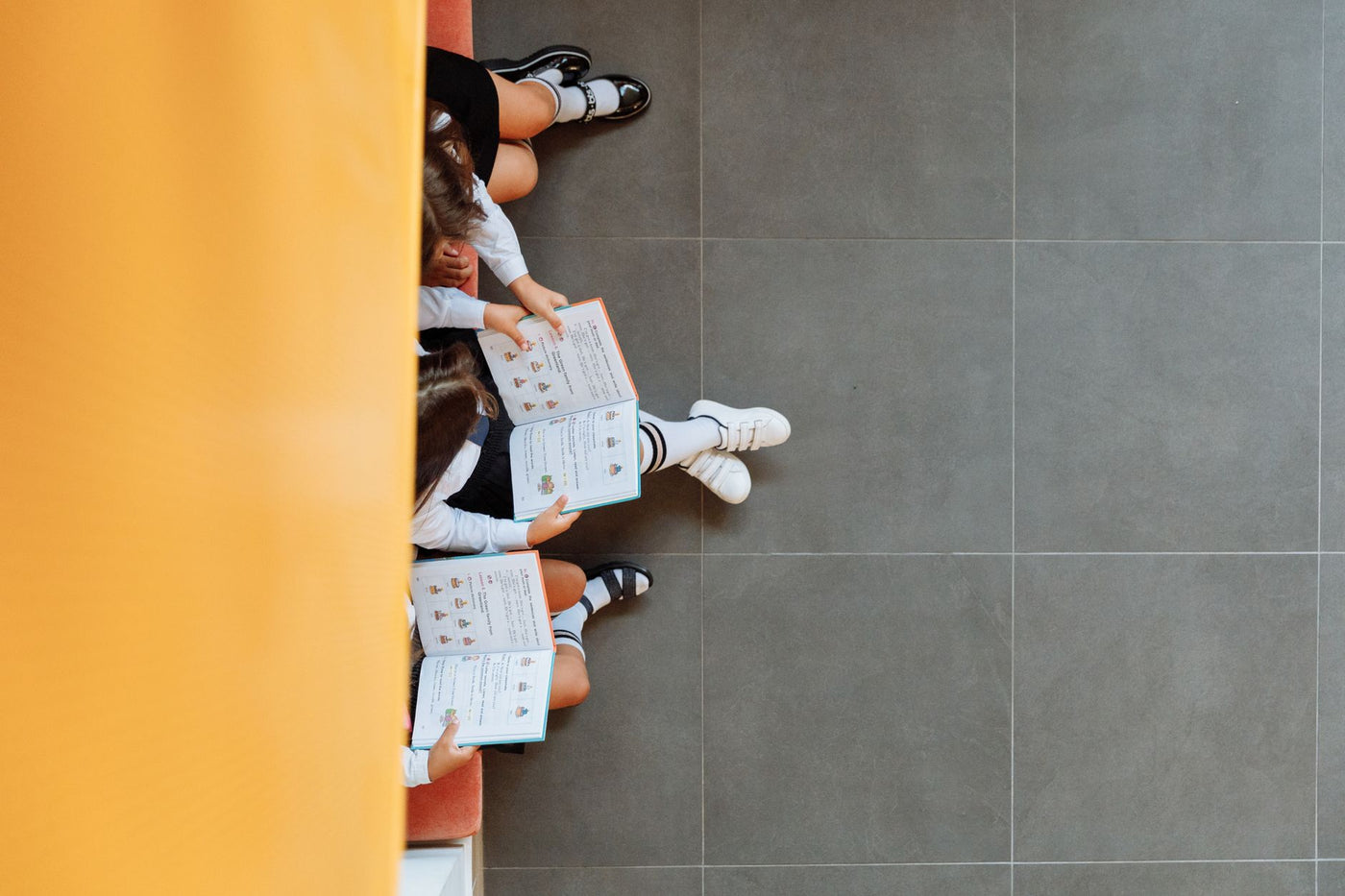 Children reading books on a school bench, viewed from above. Ideal for educational themes.