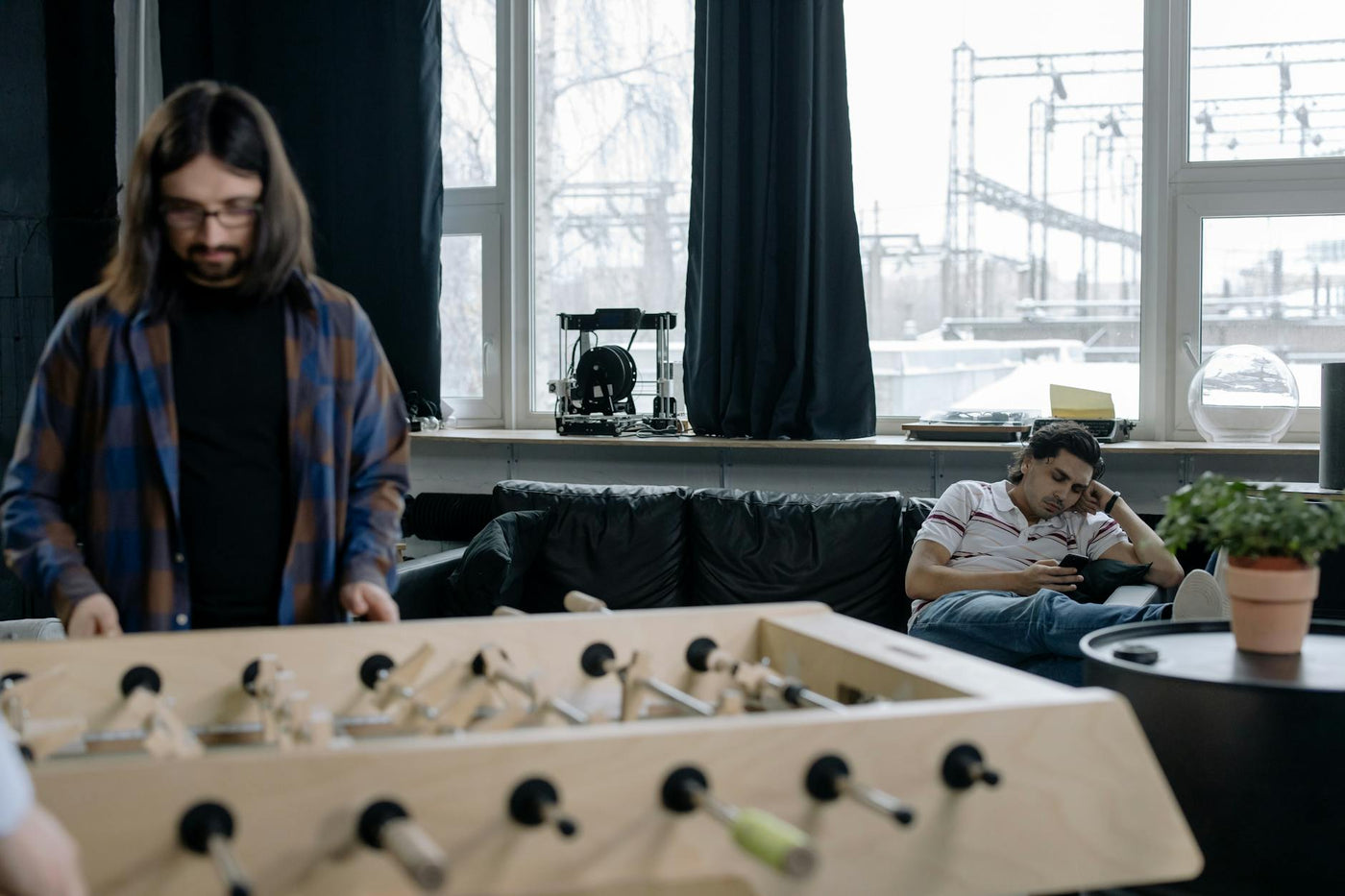 Casual office space with a foosball table and relaxing employees, ideal for teamwork or a break.