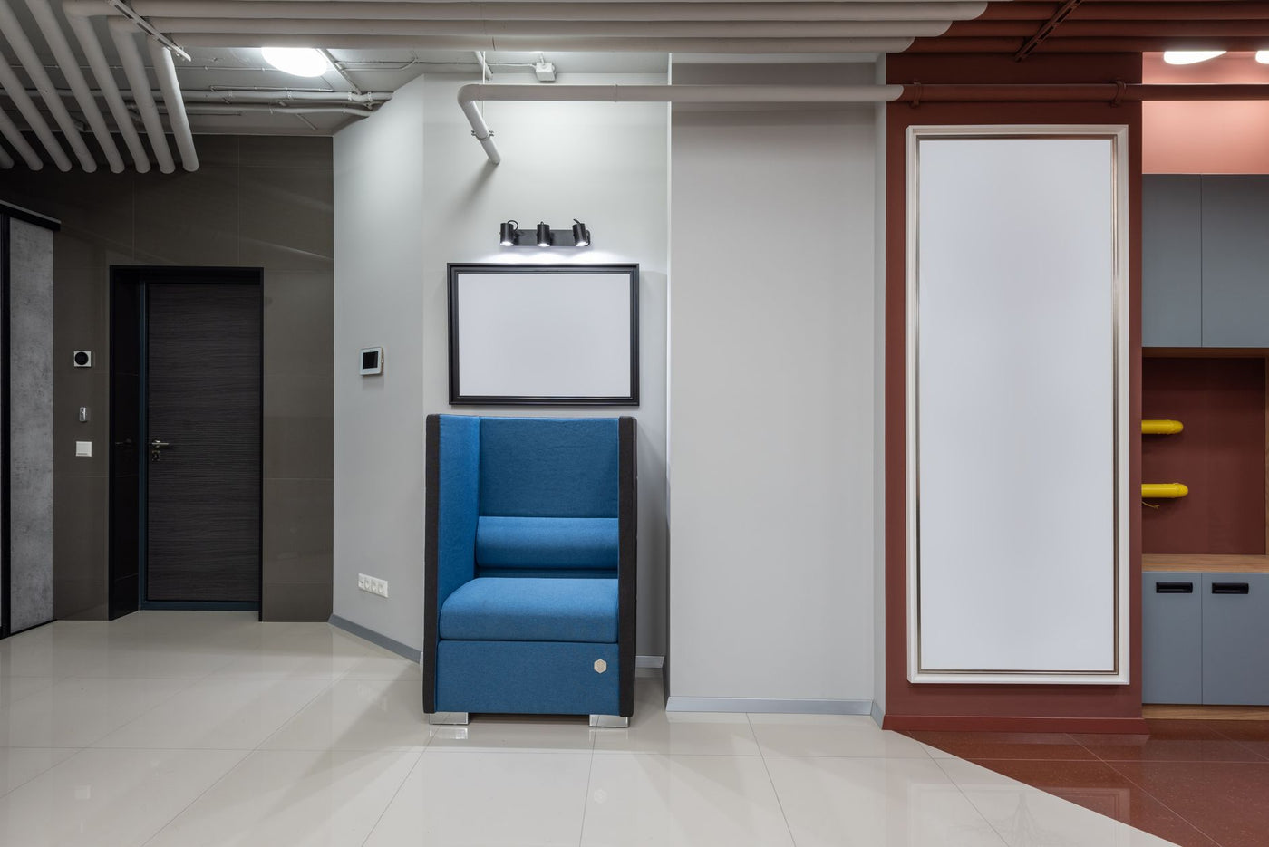 Interior of modern spacious hallway with blue armchair and entrance door leading into workplace